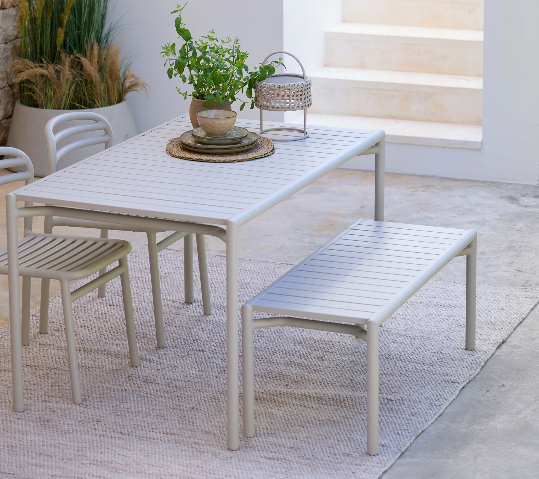 Moderne hvid spisebord med matchende bænk og stol i et minimalistisk miljø.