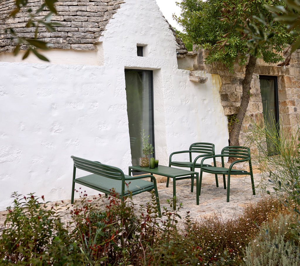 Grøn udendørs sofa og lænestole med et kaffebord i en hyggelig indstilling.