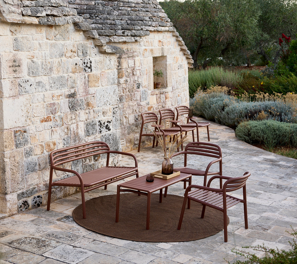 Brunt udendørs sofa, stole og bord sæt i et moderne loungeområde.