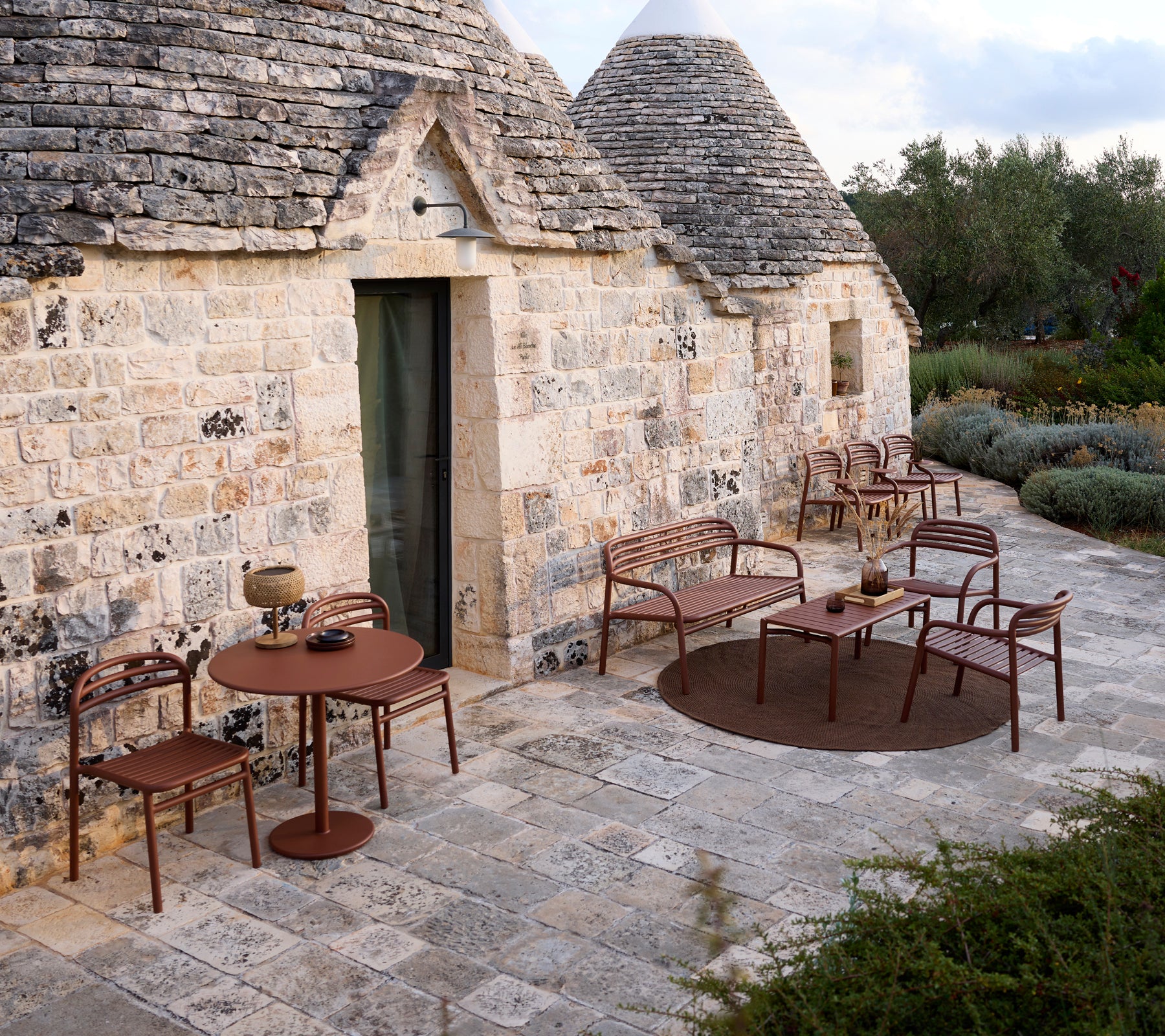 Udendørs setting med et brunt bord og stole i et moderne design.