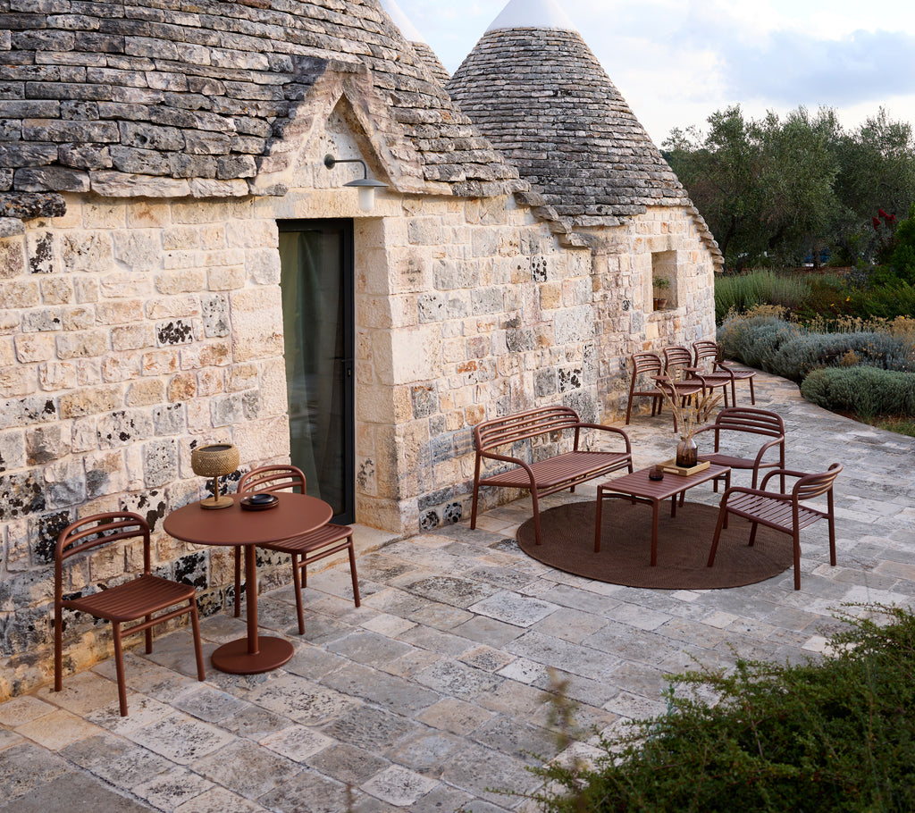 Udendørs setting med et brunt bord og stole i et moderne design.