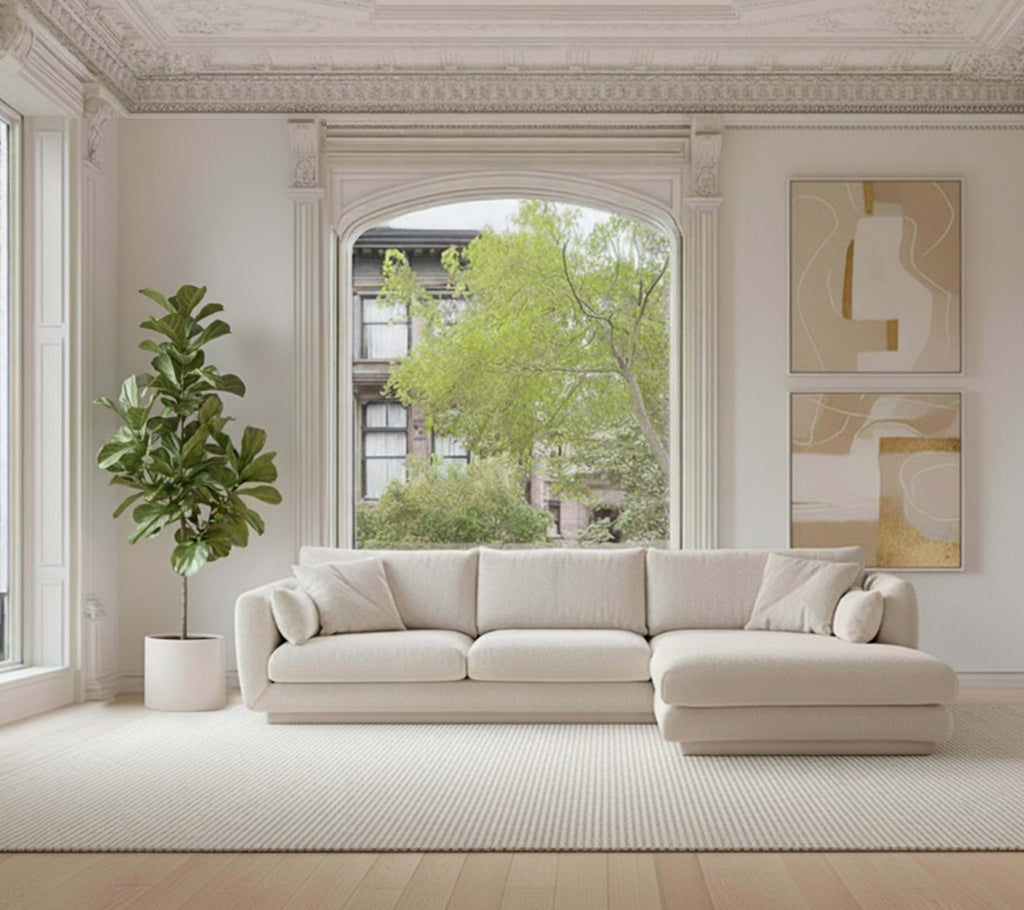 Beige sektionel sofa med en grøn plante og hvidt tæppe i en moderne loungeindretning.