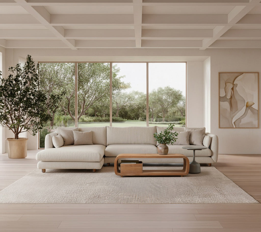 Lys grå sofa med trækaffebord og stor plante i en moderne loungestil.