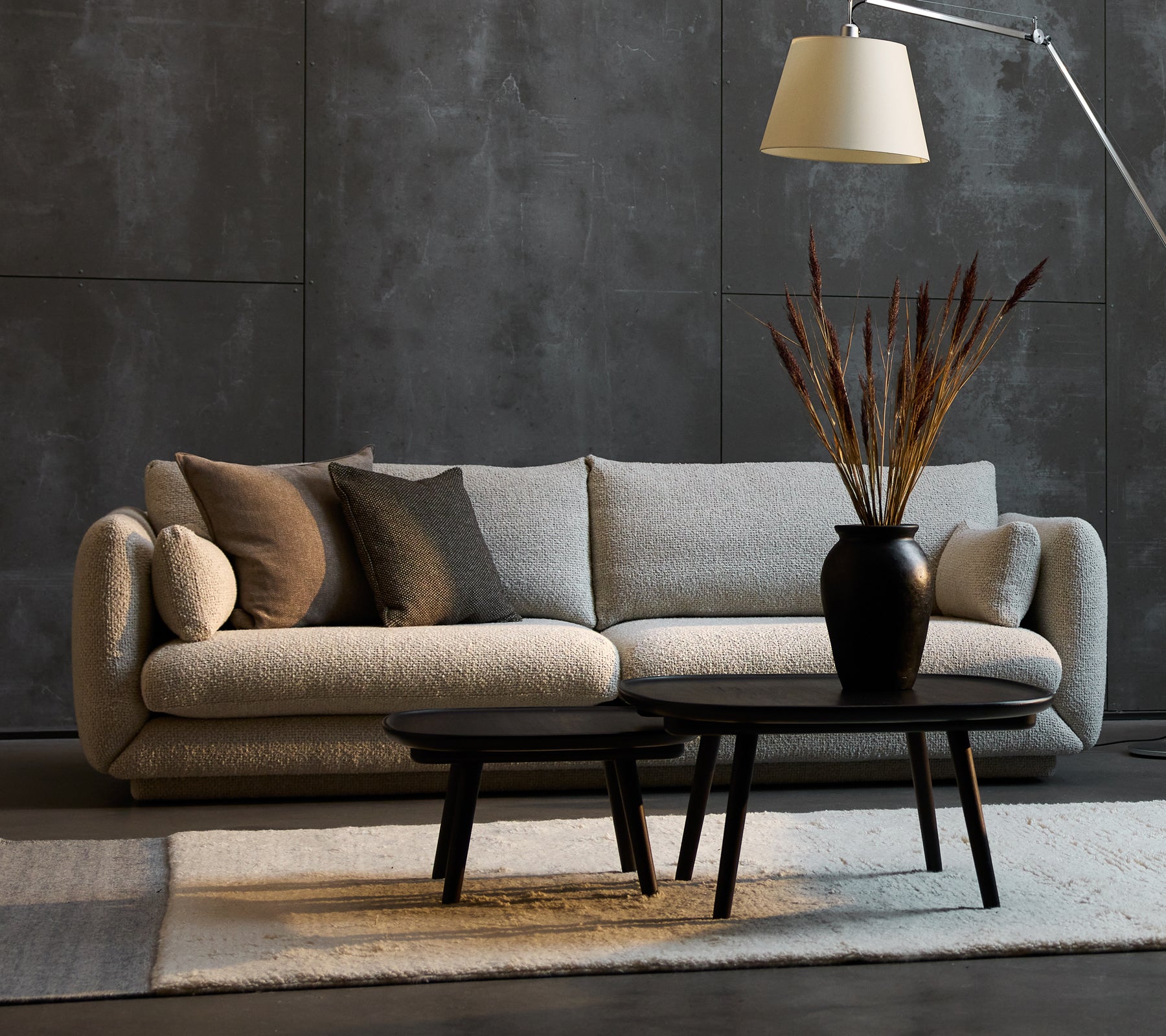 Bloom 3-personers sofa i sand farve med dekorative puder, ledsaget af to Pace sofaborde i forskellige størrelser og en stilfuld gulvlampe.