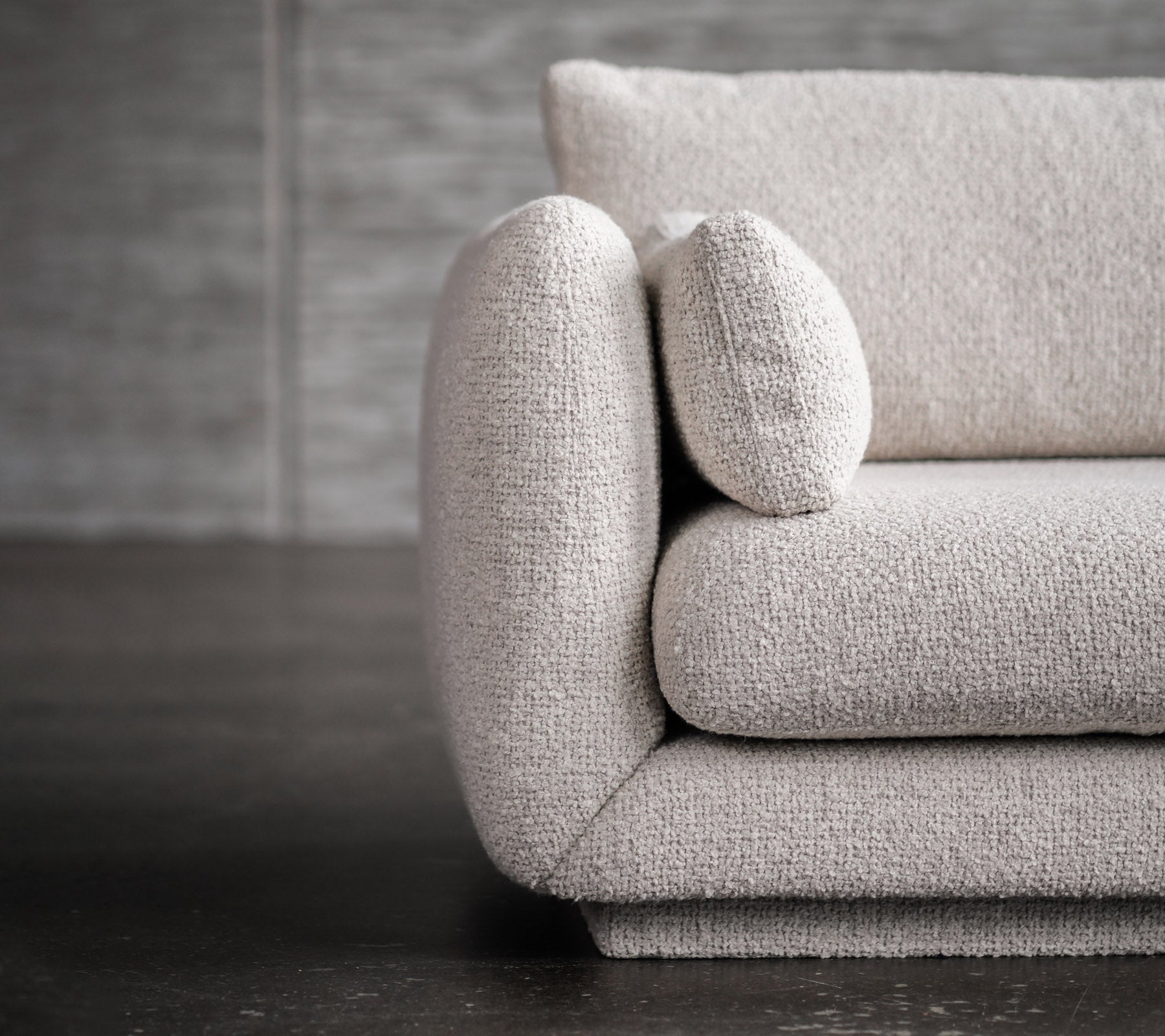 Moderne lysegrå sofa med afrundede armlæn og pude detaljer.