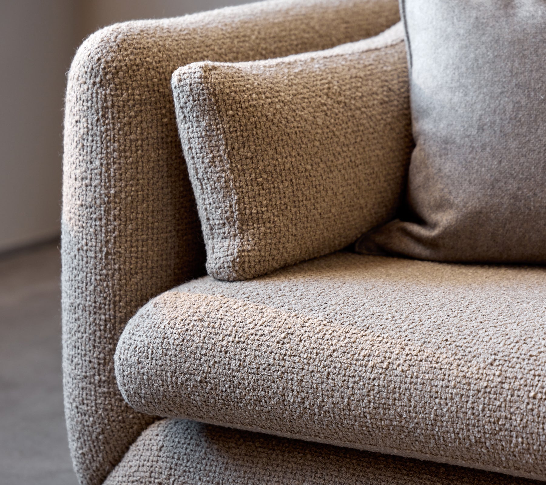 Nærbillede af et taupe Bloom-sofa-armlæn, der fremhæver dets teksturerede stof og bløde pude for ekstra komfort.