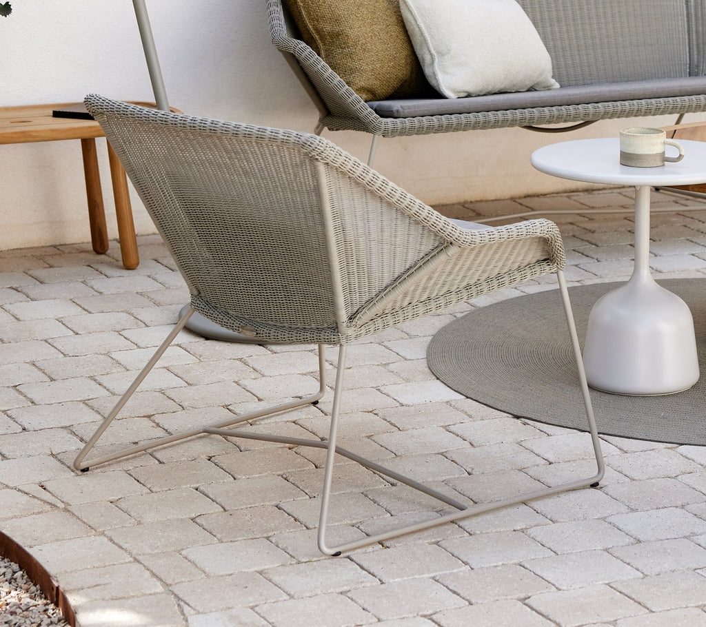 Grå loungestol med hvid sidebord i en moderne udendørs indstilling.