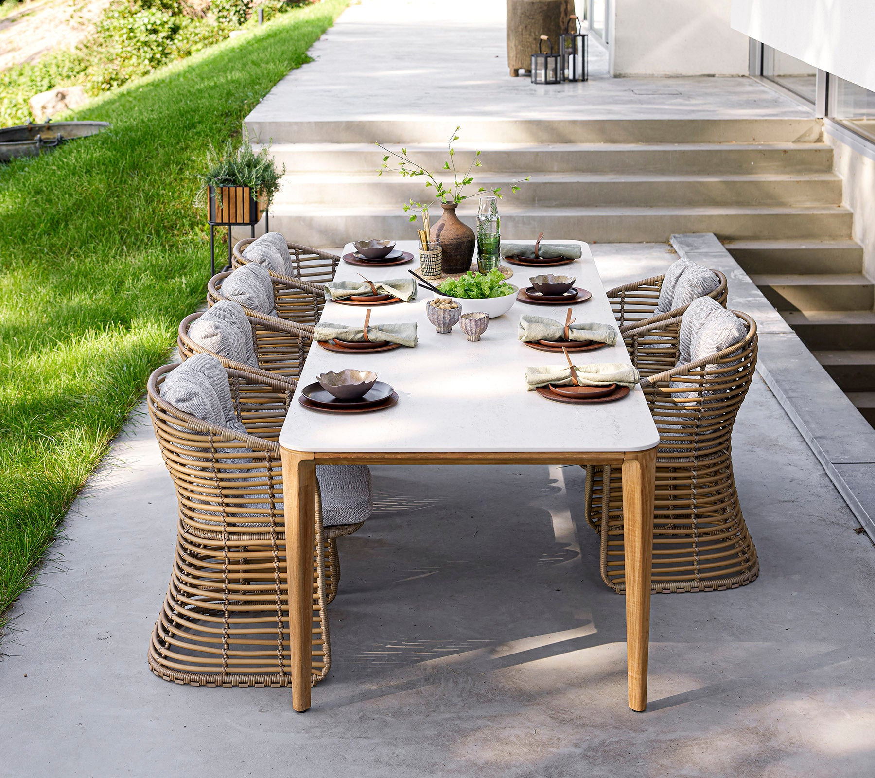 Et stilfuldt spisestuei med elegant borddækning og komfortable stole, omgivet af grønne planter og naturligt lys. Perfekt til samlinger.