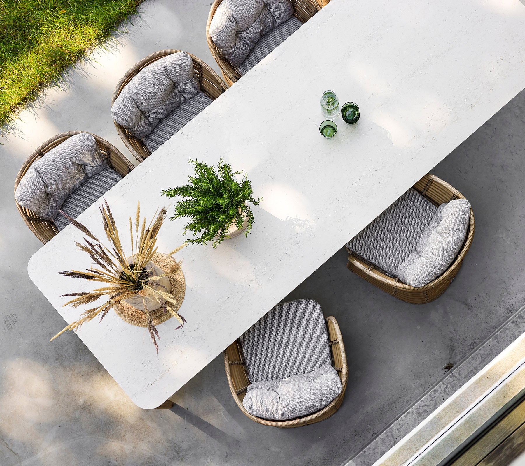 A stylish rectangular table surrounded by four comfortable chairs, adorned with greenery and decorative elements on top.