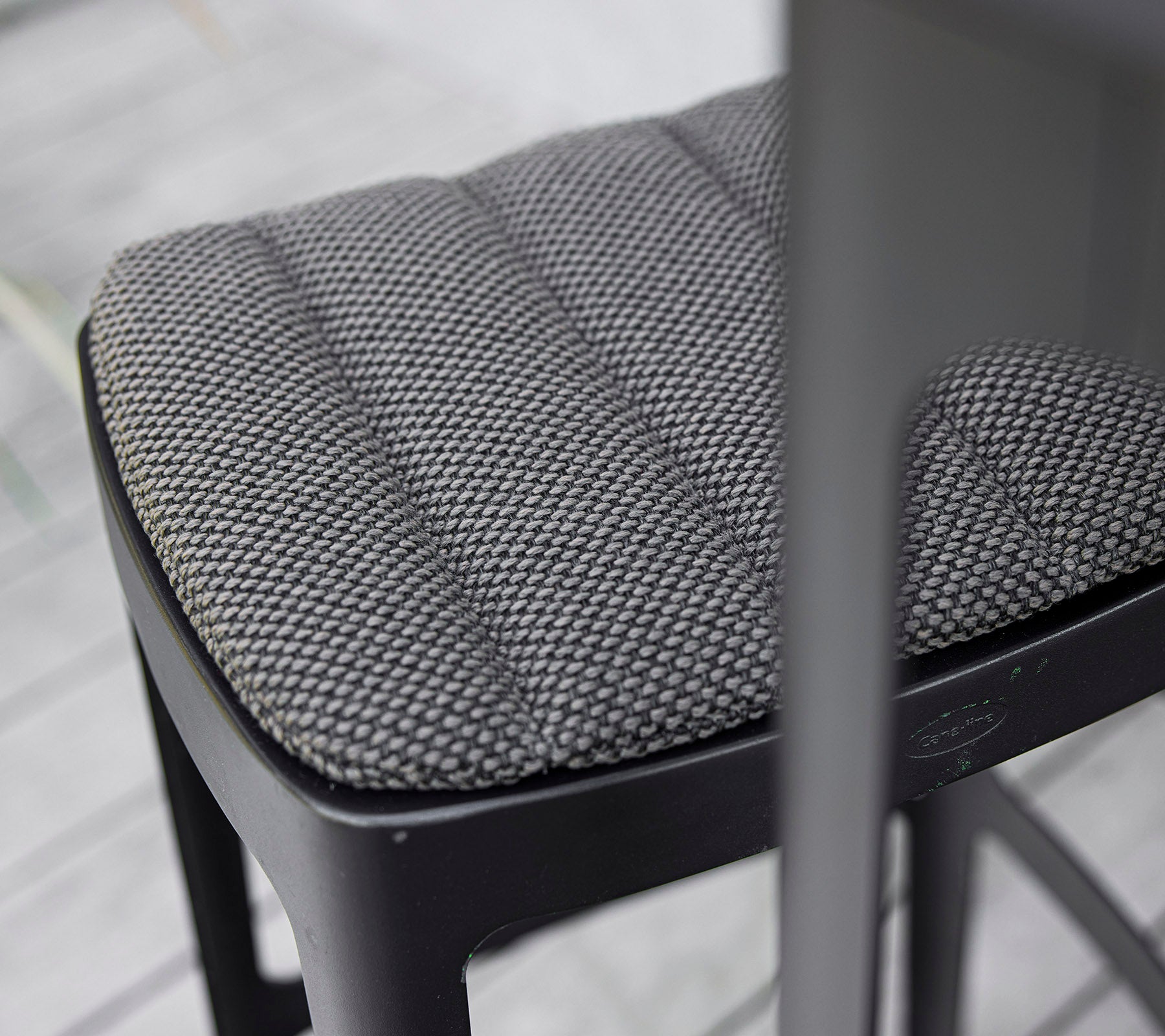 Nærbillede af en tekstureret sort stolseparat med en quiltet design, der viser moderne håndværk og opmærksomhed på detaljer.