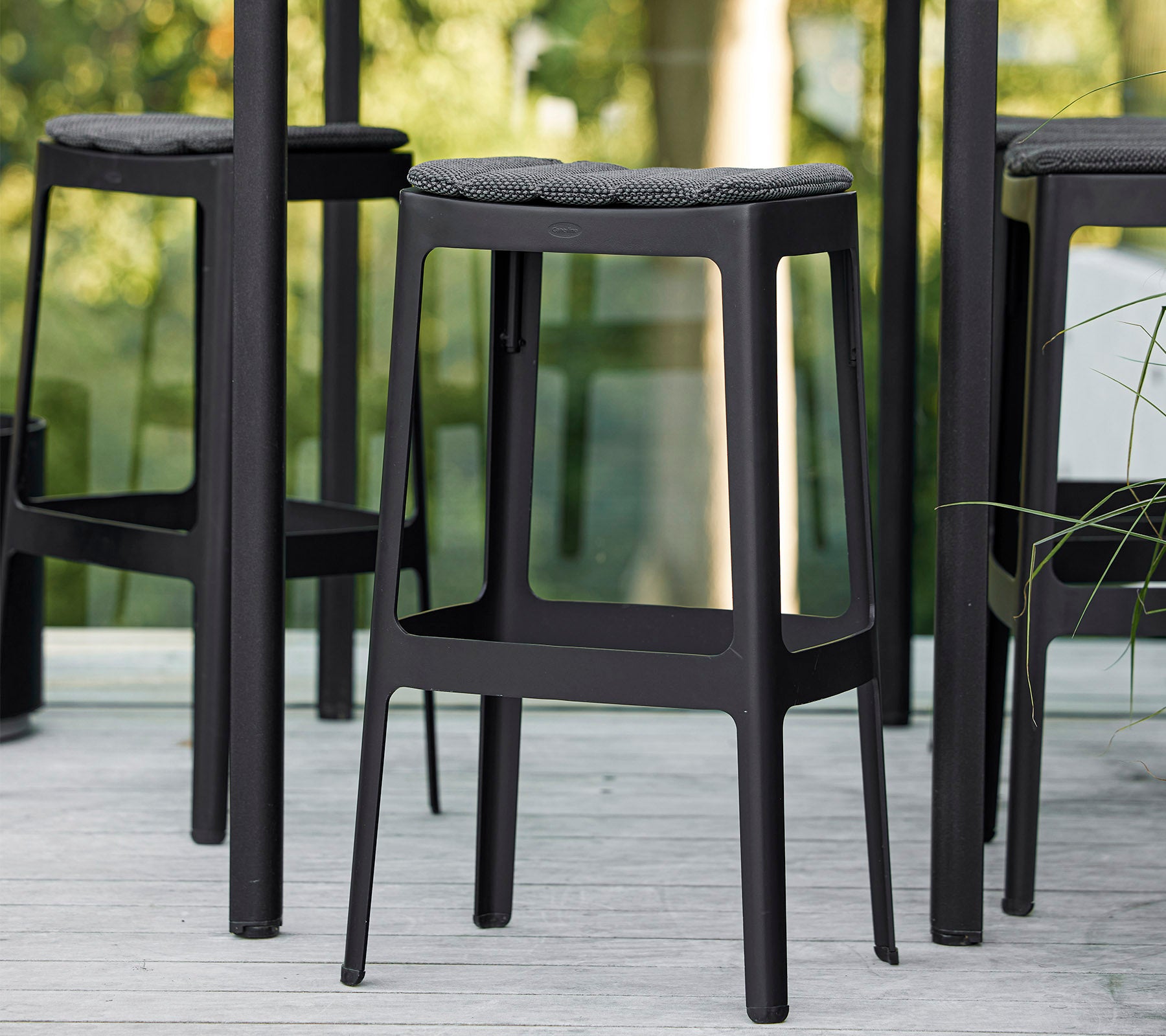 Sorte barstole med minimalistisk design og polstrede sæder, arrangeret tæt sammen og viser en moderne æstetik.