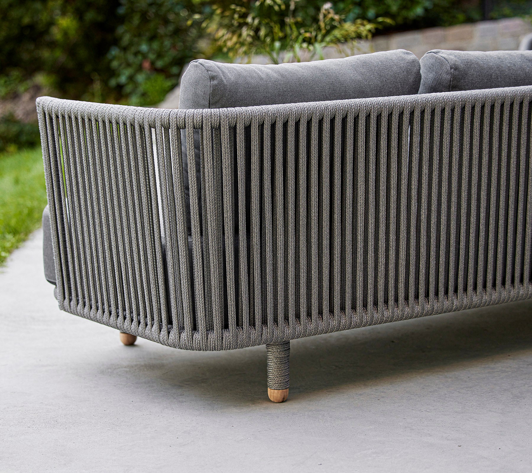 Slank, moderne grå sofa med vertikale slatsdesign og træben, ideel til moderne udendørs eller indendørs rum.
