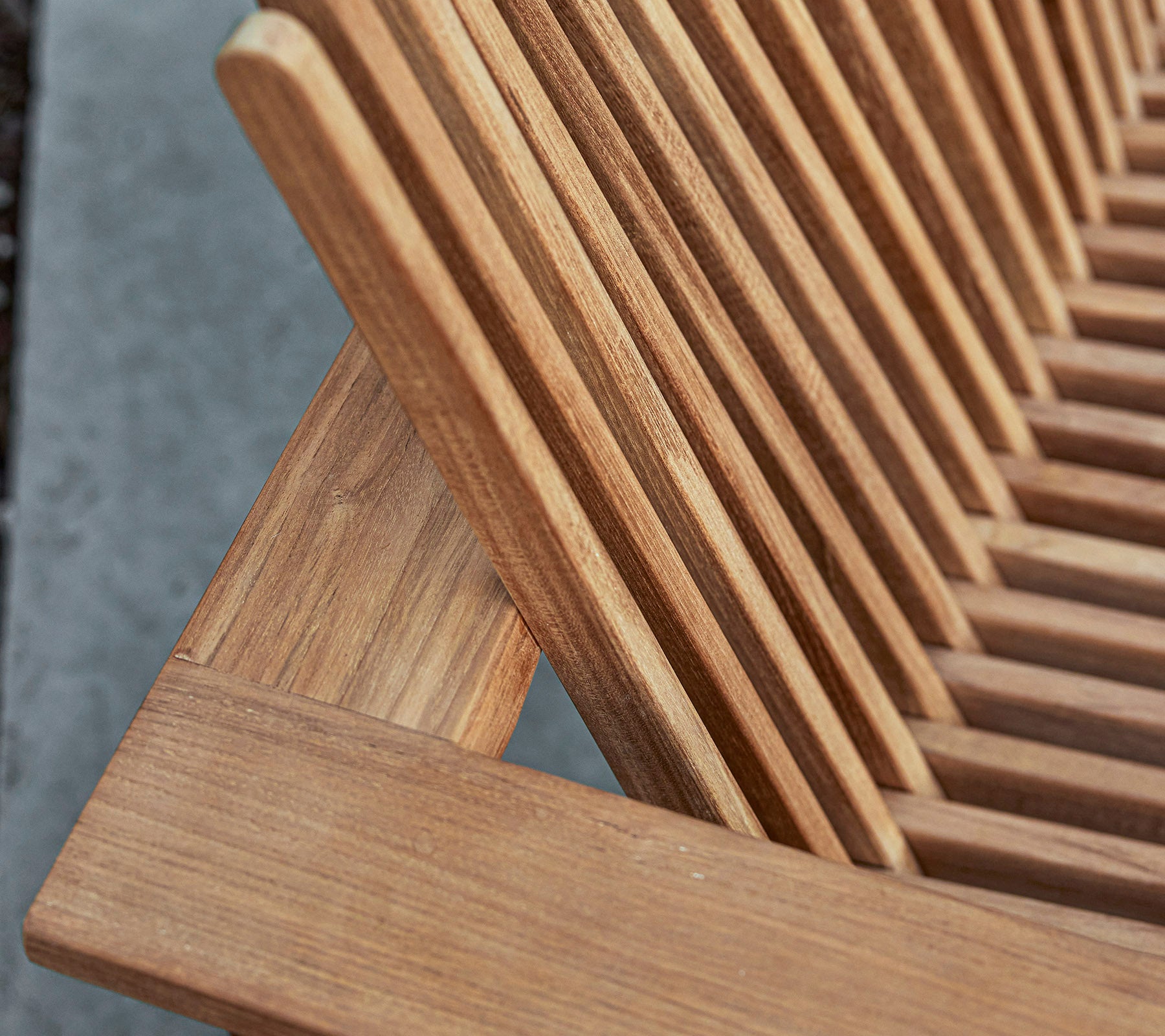 Nærbillede af et stykke træmøbel med en lamel-design, der viser den naturlige åretegning og håndværksdetaljer.