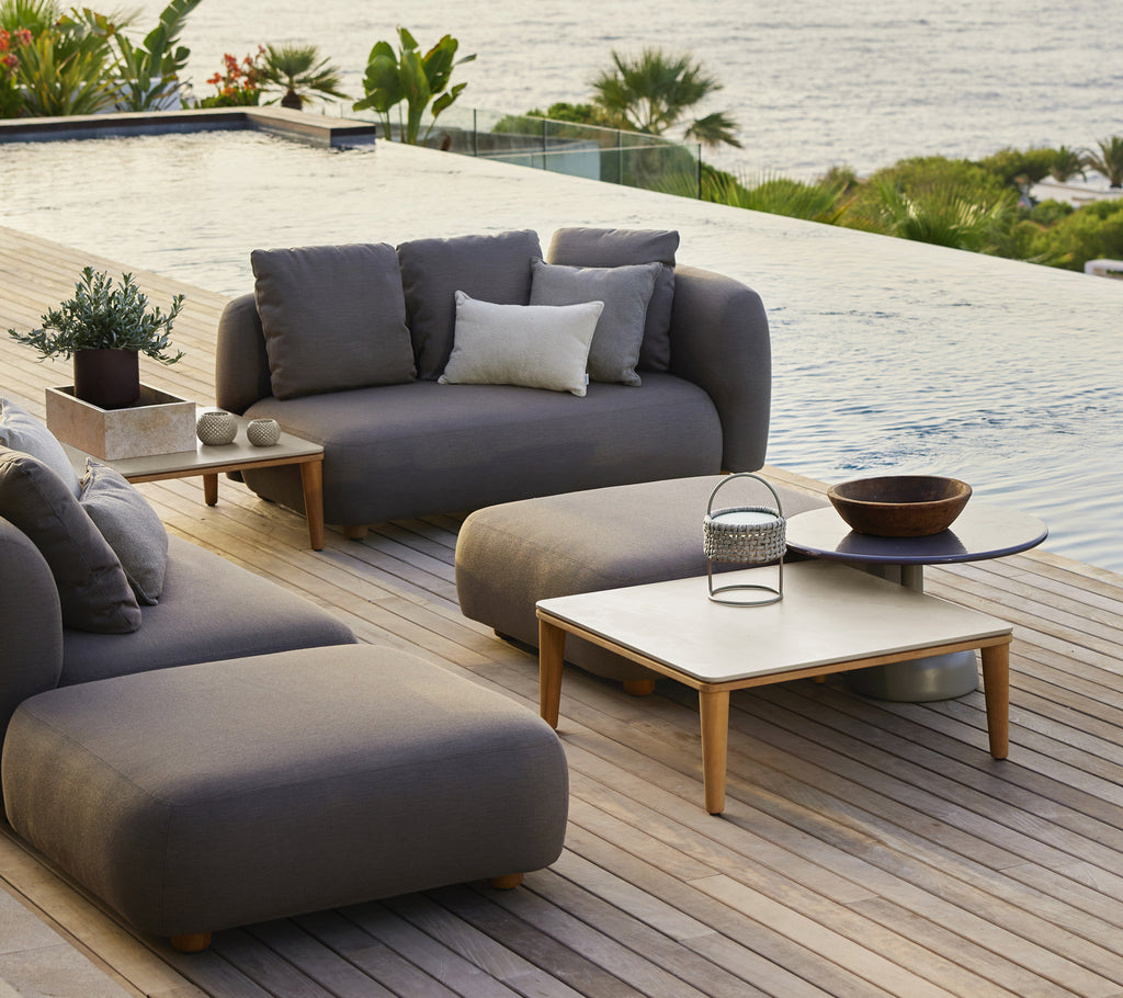 Moderne udendørs lounge møbler med grå sofa, sæde og trækaffebord.