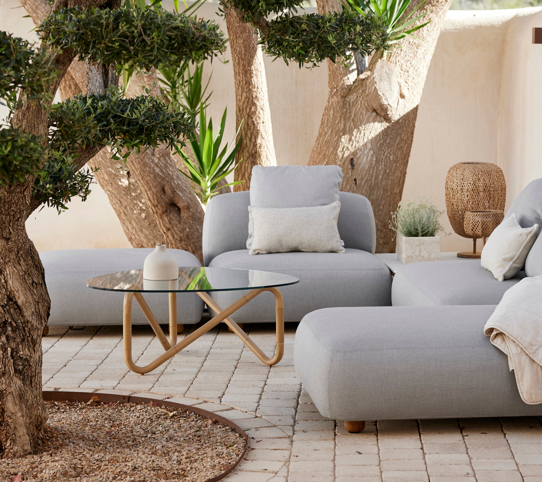 Moderne loungeområde med en grå sofa, hvid pude og glastable.