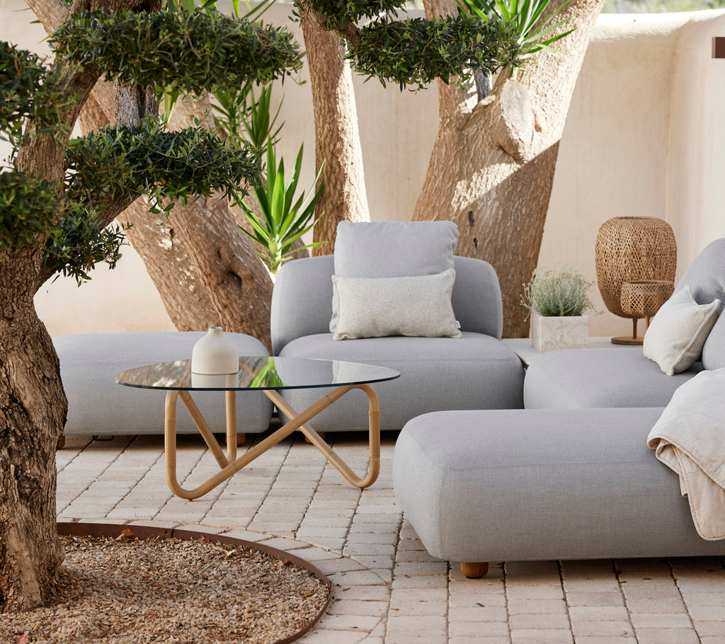 Moderne loungeområde med en grå sofa, hvid pude og glastable.
