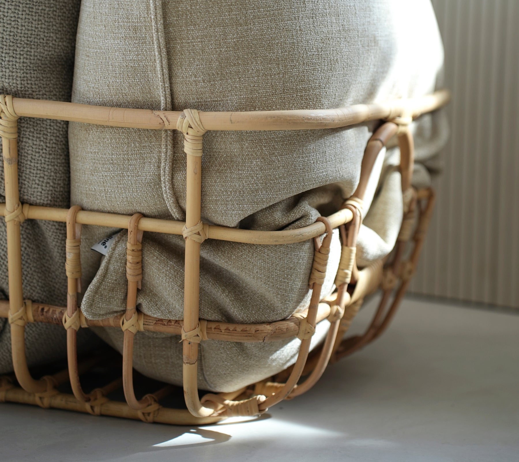 Beige pude gemt i en flettet kurv, der fremviser en bohemian æstetik.