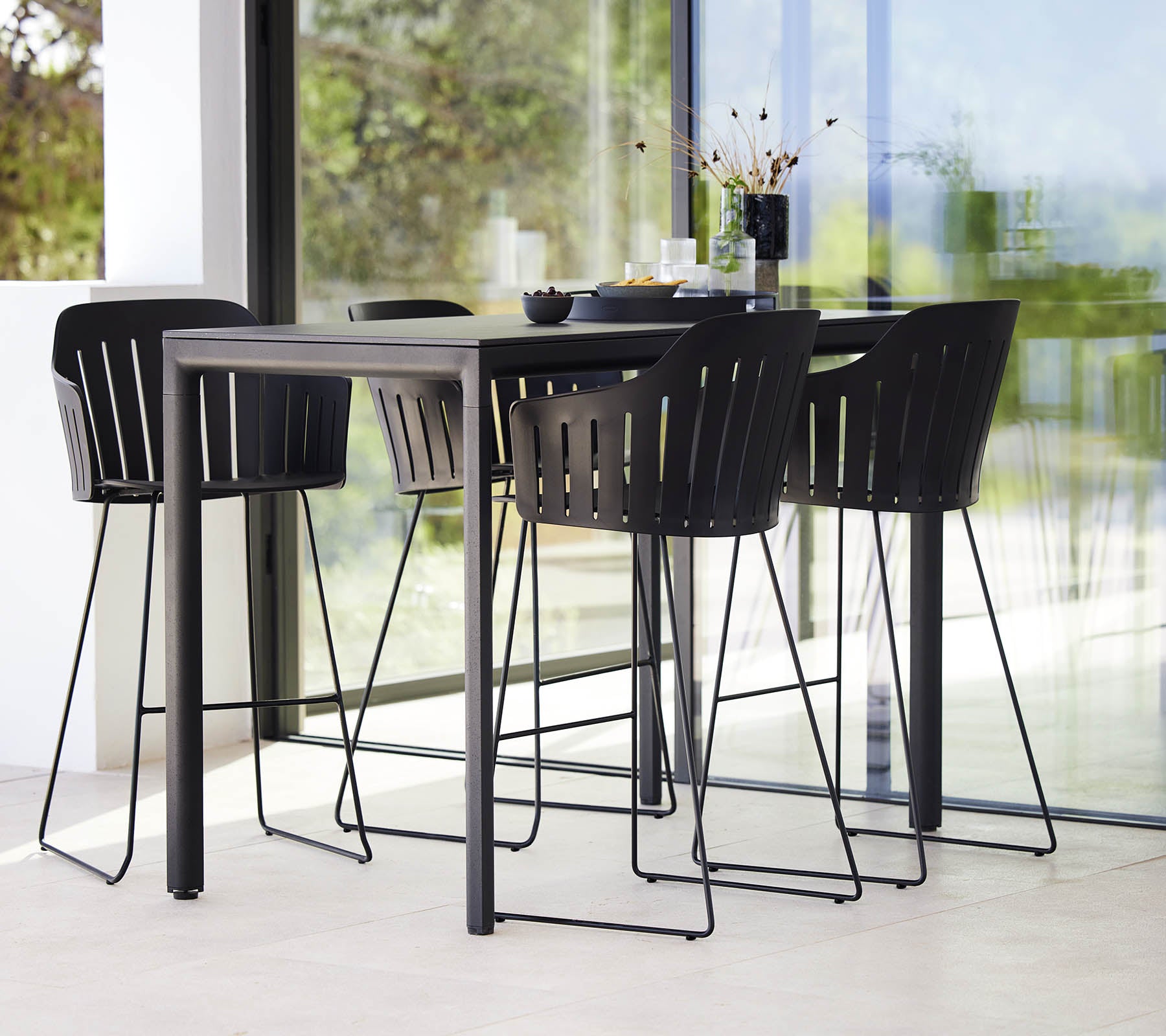Et slankt sort bardisk parret med moderne barkstole med en lamel design, der skaber en stilfuld siddearrangement.
