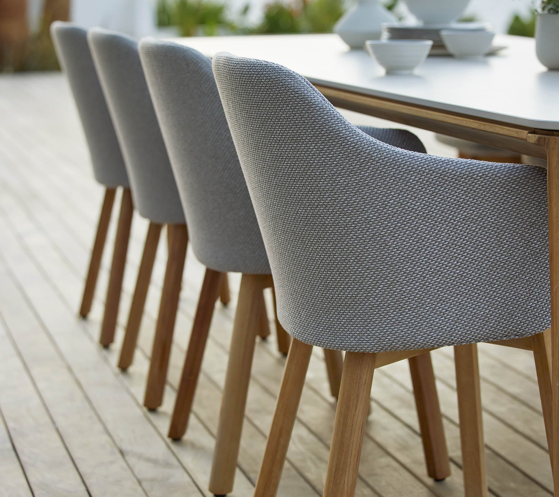 En række moderne polstrede stole med træben, der er pænt arrangeret ved siden af et bord, der viser et stilfuldt og moderne design.