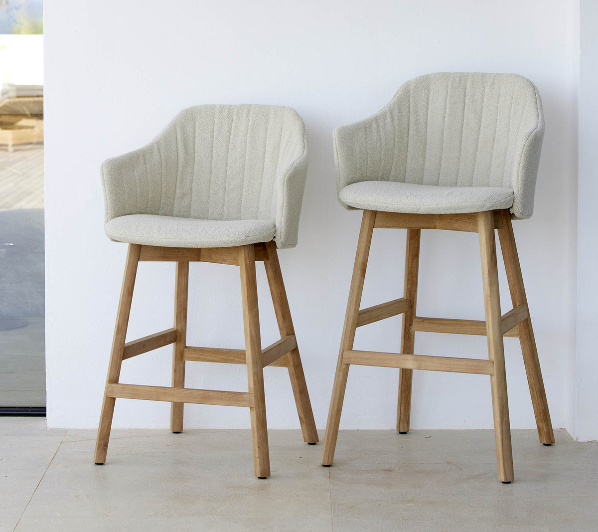 To stilfulde, lyse stole med buede rygge og træben, der viser et moderne og komfortabelt design.