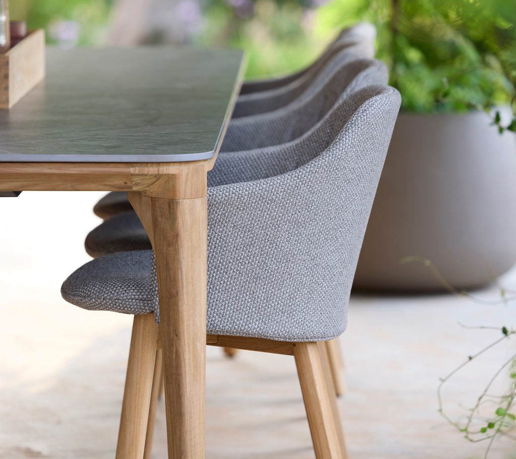 Moderne grå stol og bord i en rolig udendørs omgivelser.