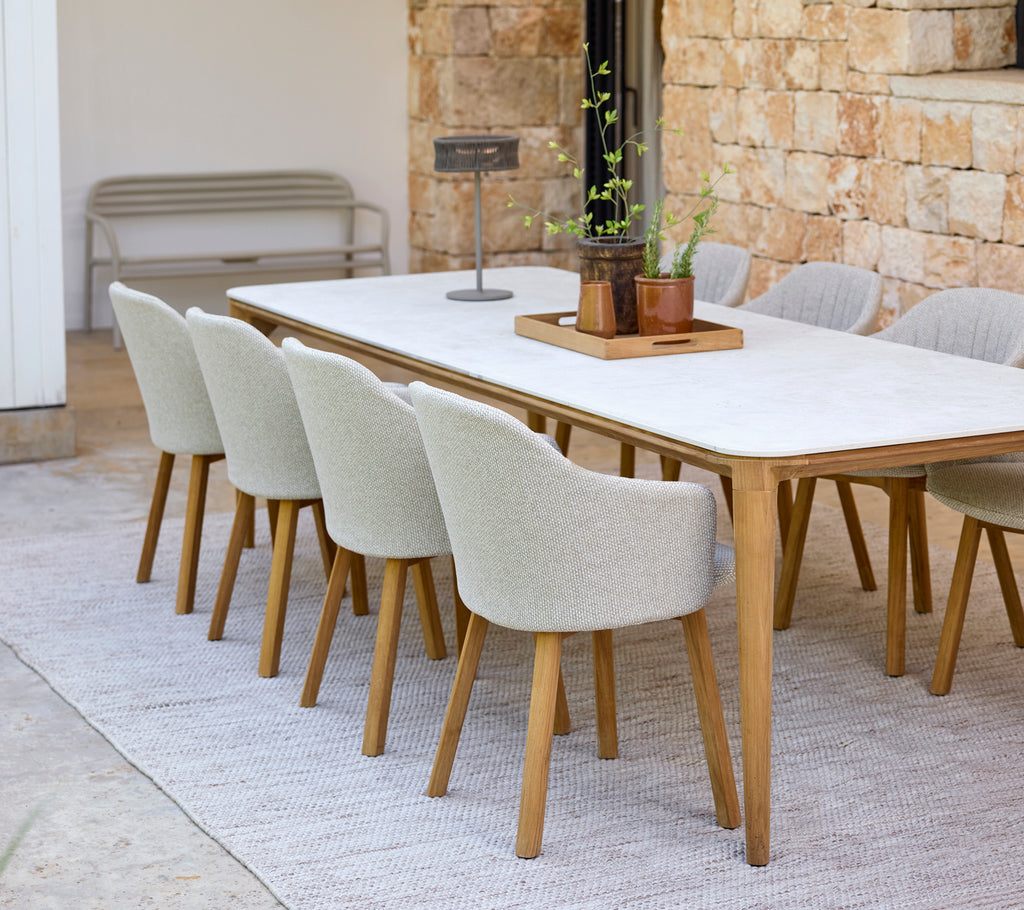 Moderne spiseopsætning med et hvidt bord og beige stole.