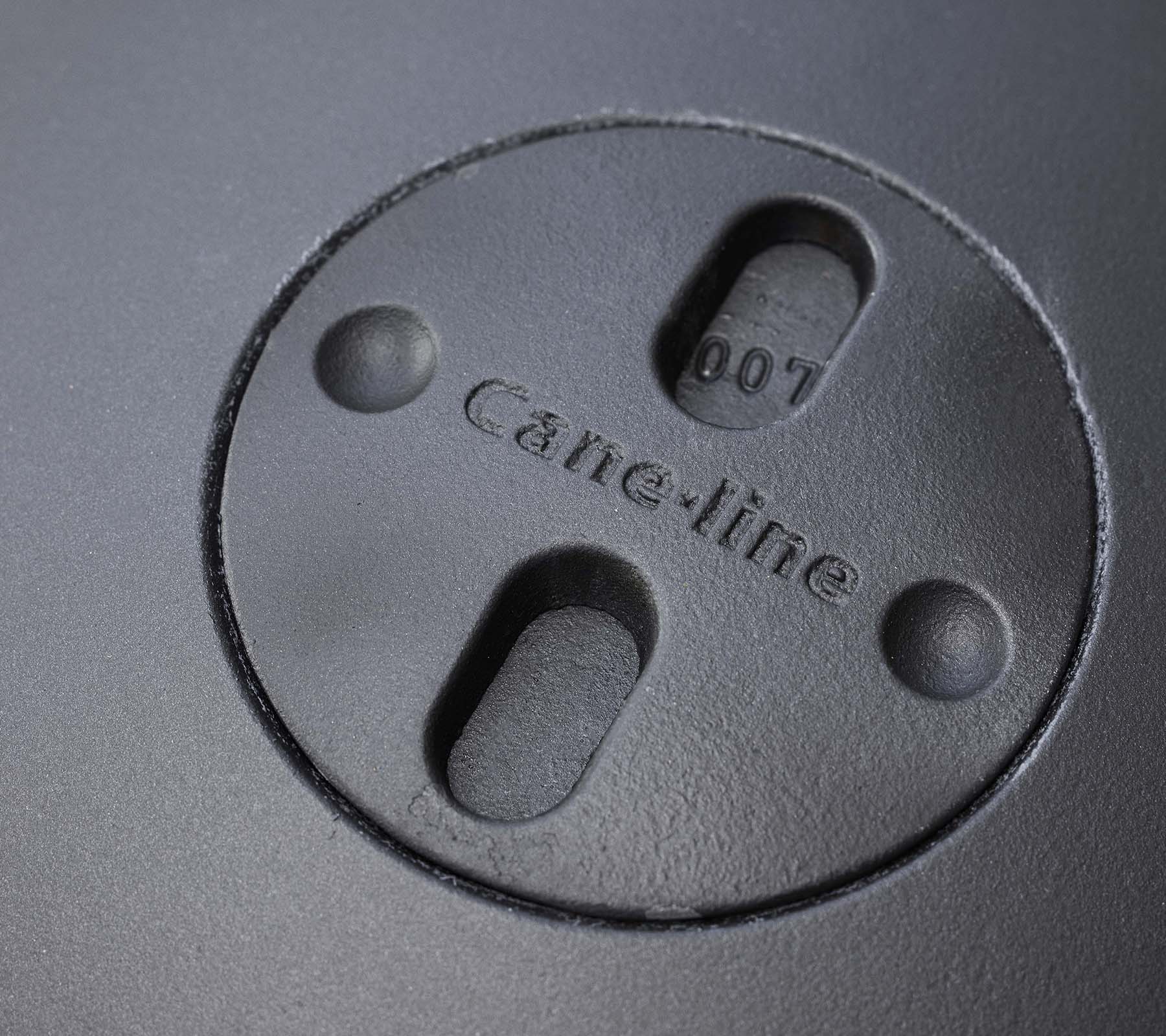 Nærbillede af et cirkulært element med indgraveret "Cane-line" logo og to spor, en del af et bålsteddesign.