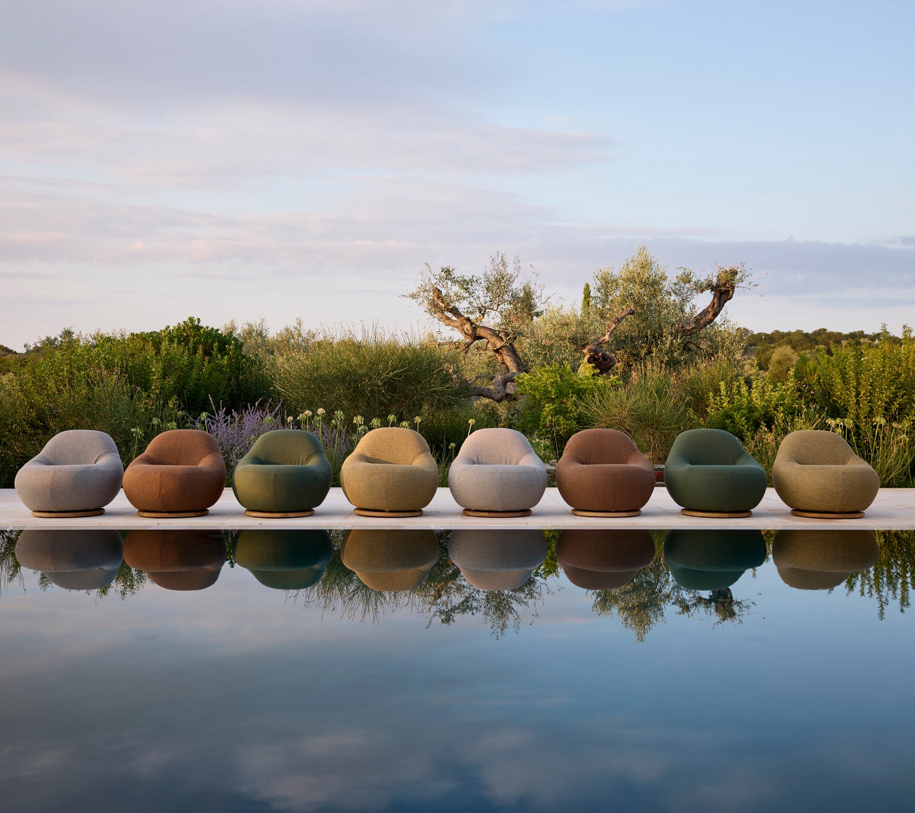 Moderne udendørsstole i forskellige farver arrangeret ved poolen.