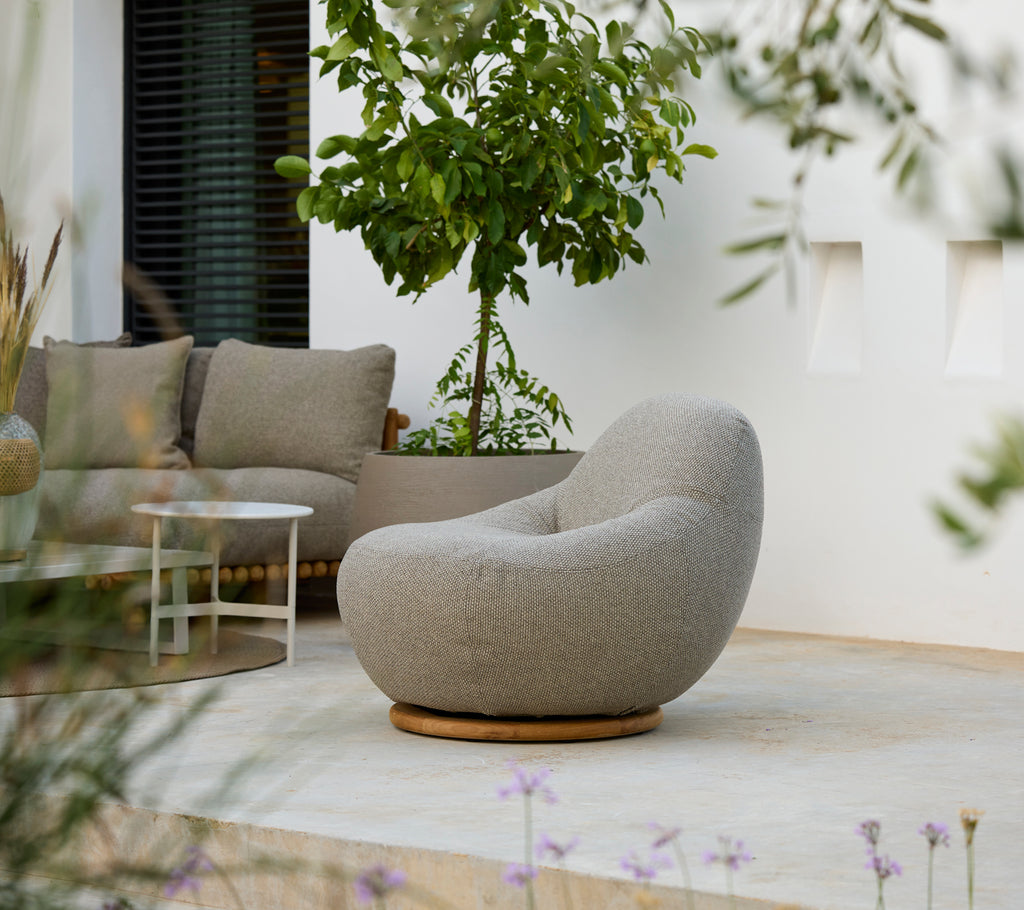 Moderne loungeindretning med en grå stol, grå pude og hvidt bord.