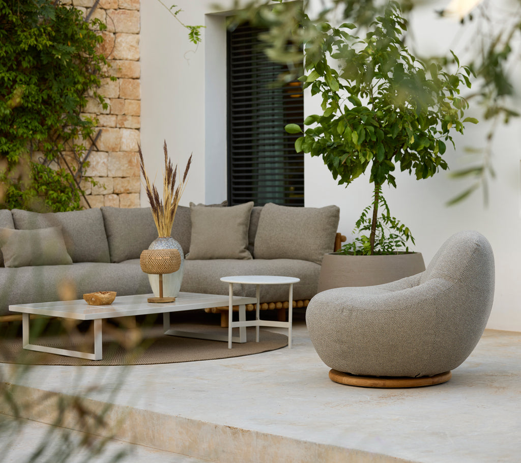 Moderne loungeområde med en grå sektionals Sofa, hvidt kaffebord og rund stol.