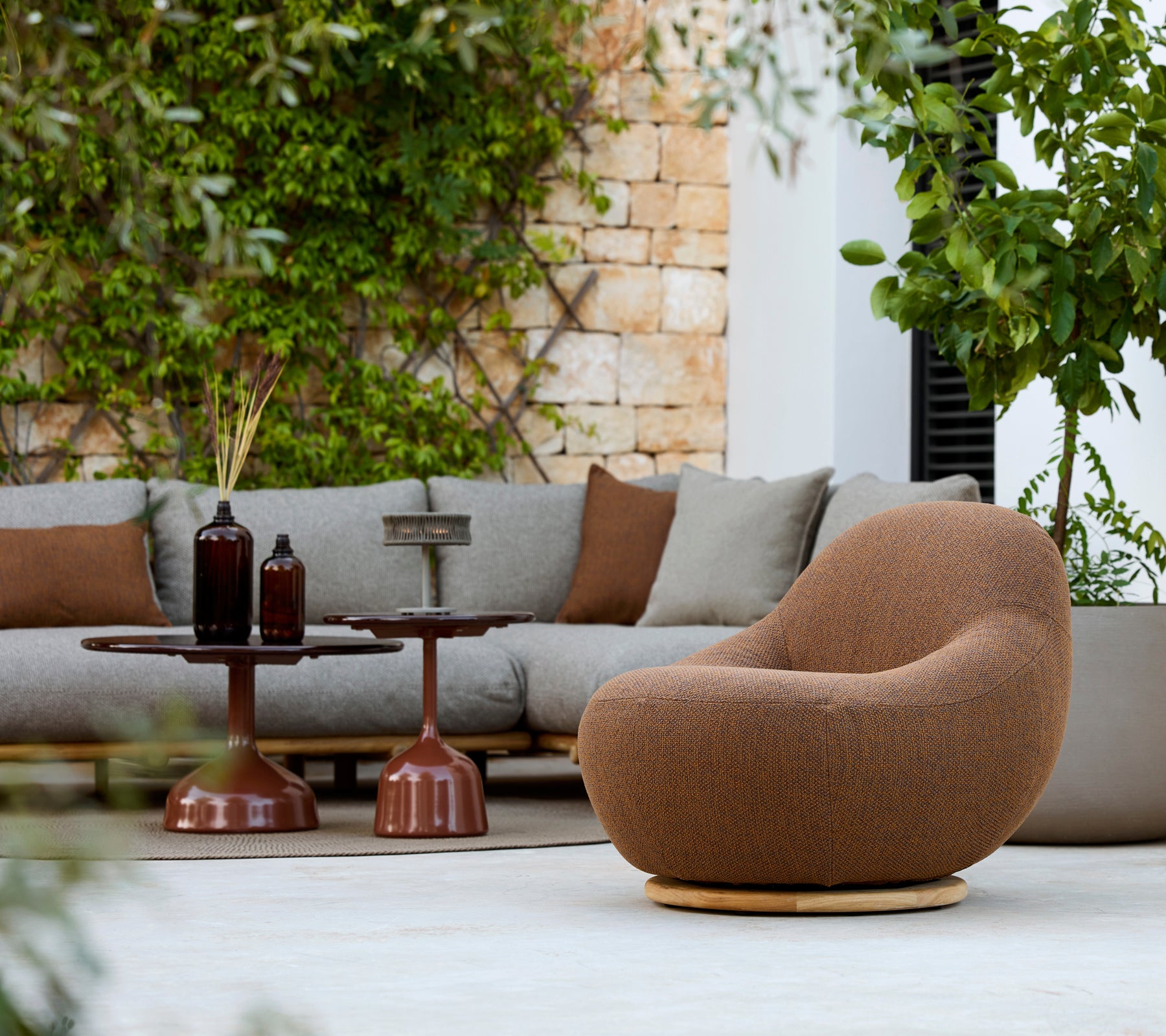 Moderne loungeområde med en brun lænestol, grå sofa og brun sidebord.