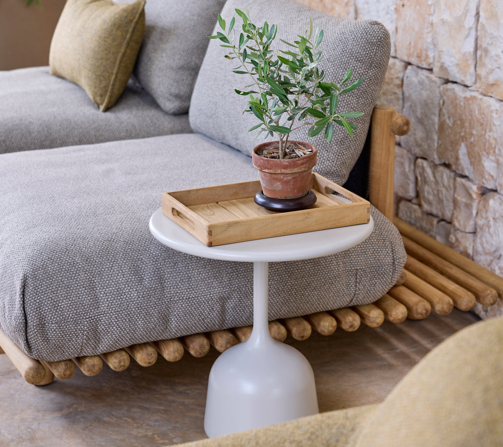 Moderne loungeindretning med en grå sofa, et hvidt sidebord og en grøn plante.