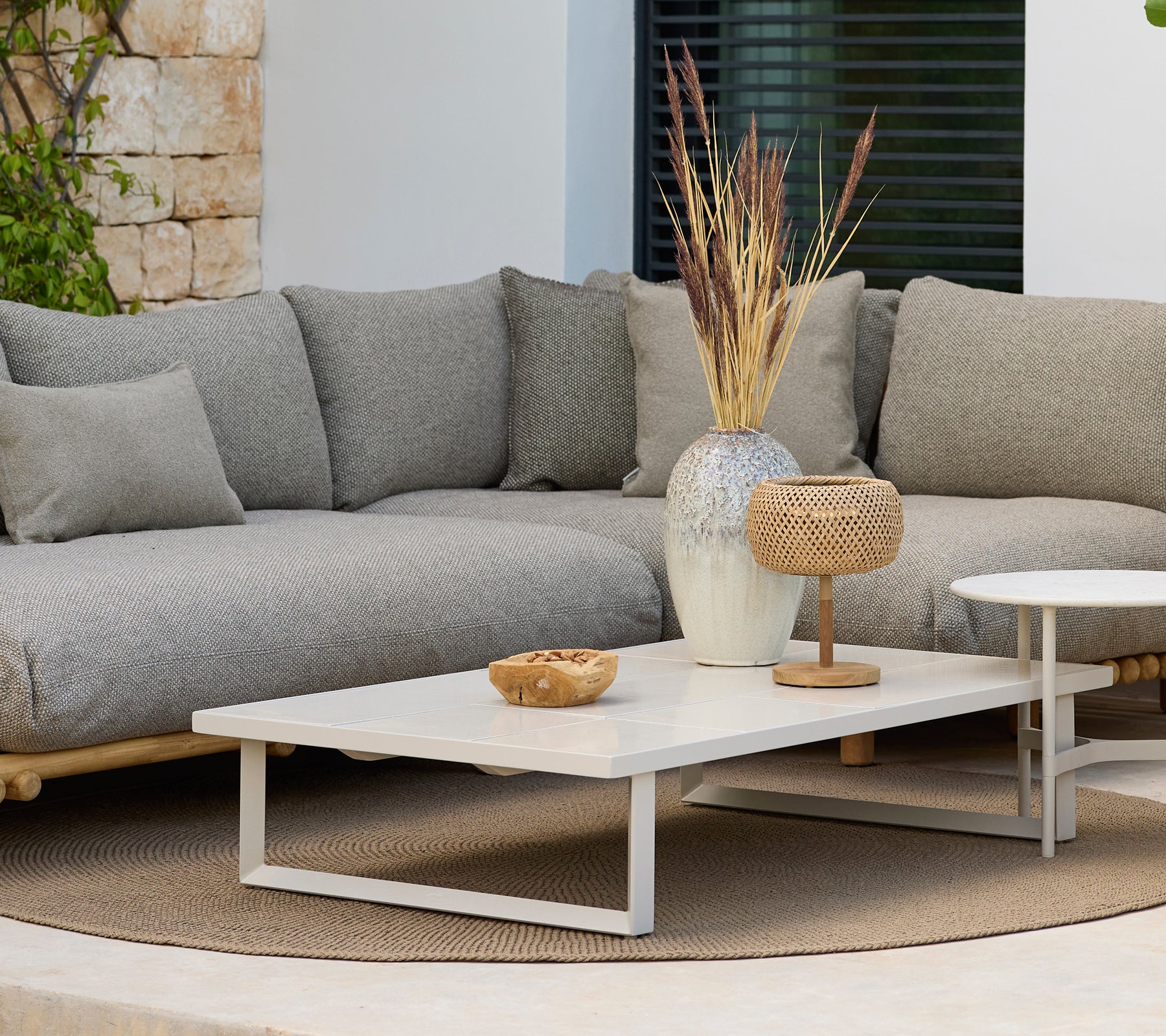 Moderne loungeområde med en grå sofa og et hvidt sofabord med dekoration.