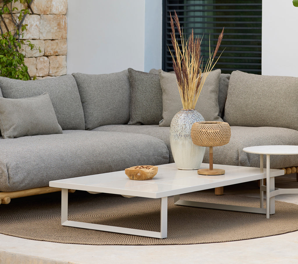 Moderne loungeområde med en grå sofa og et hvidt sofabord med dekoration.