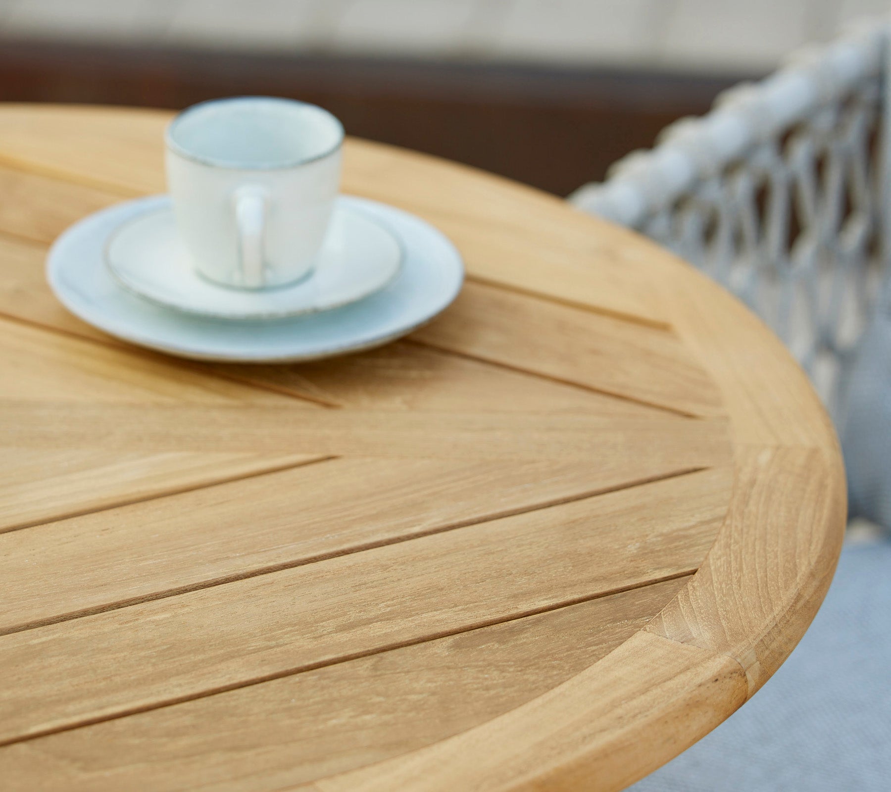 Et træbord med en kaffekop og saucer ovenpå, der viser et minimalistisk og indbydende cafémiljø.