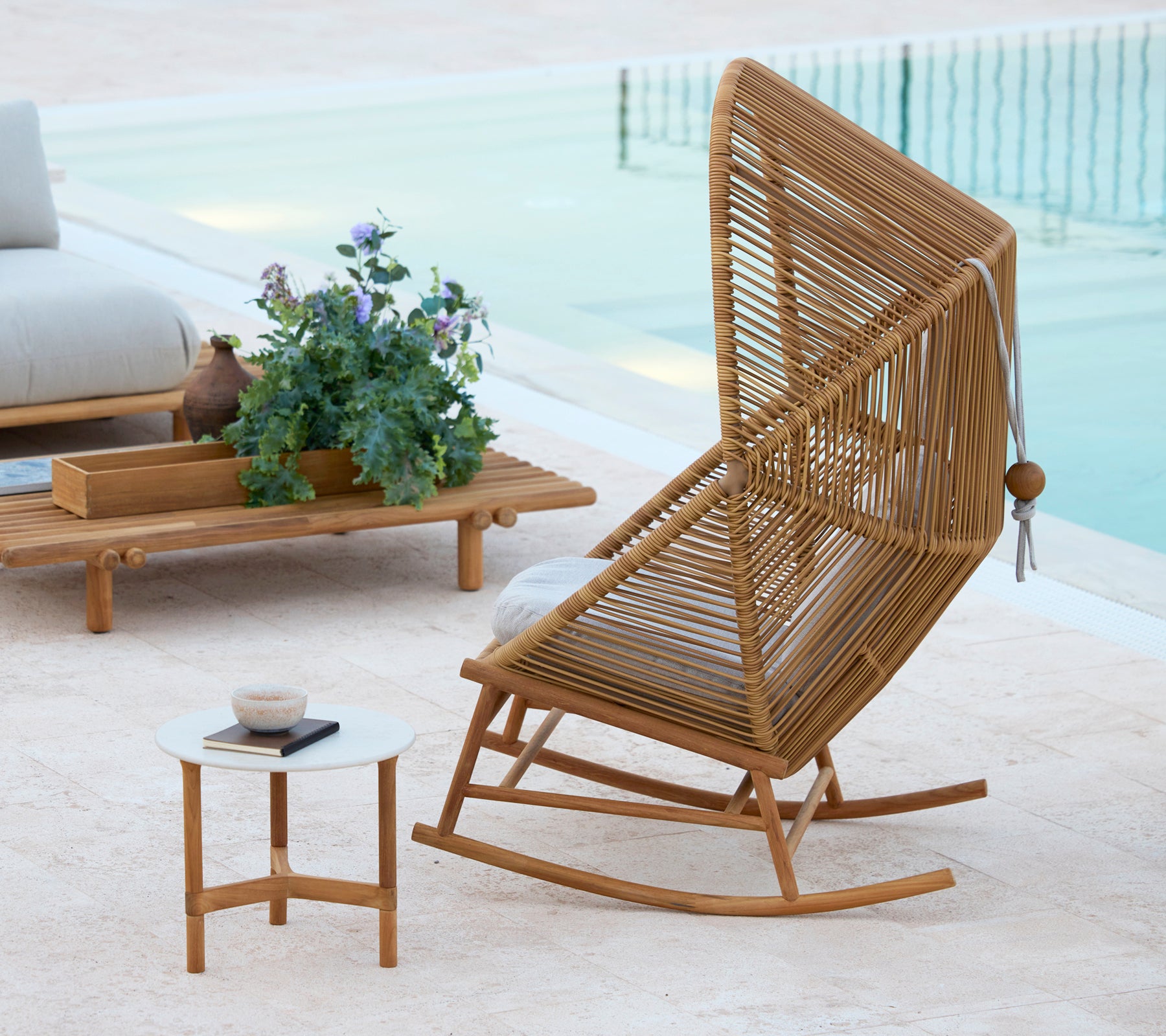 En stilfuld Hive gyngestol ved siden af ​​et Twist kaffebord og et Sticks kaffebord, suppleret af en potteplante.