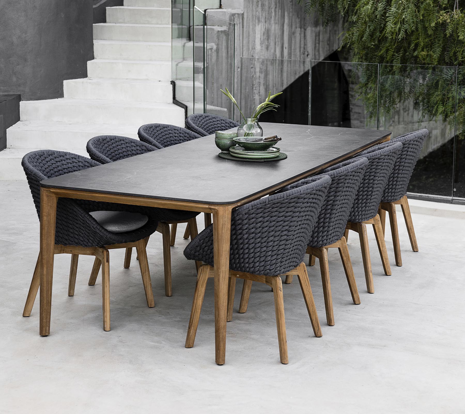 Et moderne bord omkranset af otte stilfulde stole, udsmykket med dekorative planter på bordet i et strømlinet, minimalistisk miljø.