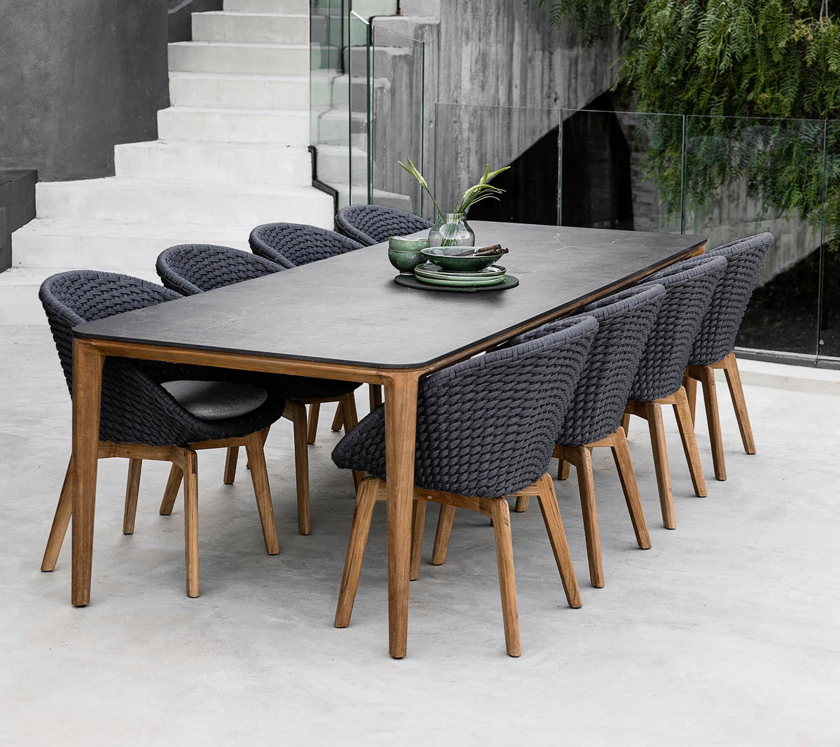 Et moderne bord omkranset af otte stilfulde stole, udsmykket med dekorative planter på bordet i et strømlinet, minimalistisk miljø.