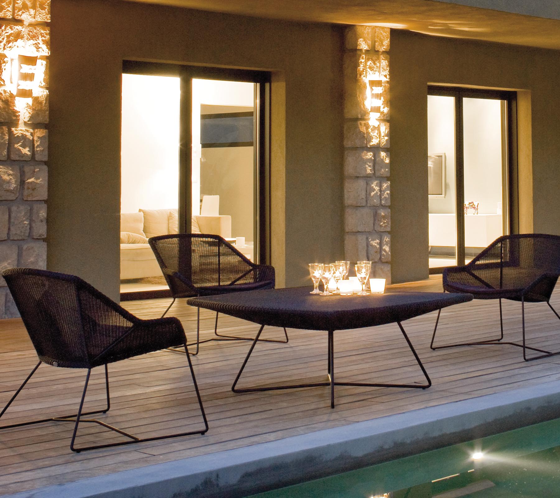 Et stilfuldt lounge seating arrangement med fire sorte netstole omkring et slankt bord, oplyst af blødt ambient belysning.