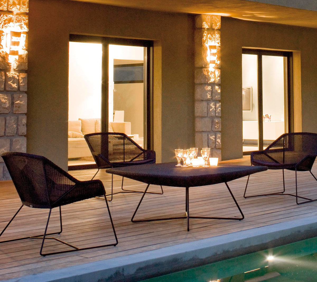 Et stilfuldt lounge seating arrangement med fire sorte netstole omkring et slankt bord, oplyst af blødt ambient belysning.