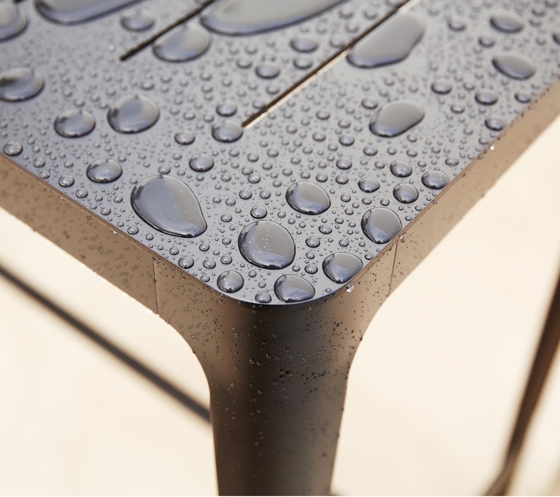 Nærbillede af en struktureret overflade med vanddråber, der fremhæver det slanke design og detaljerne i materialet.