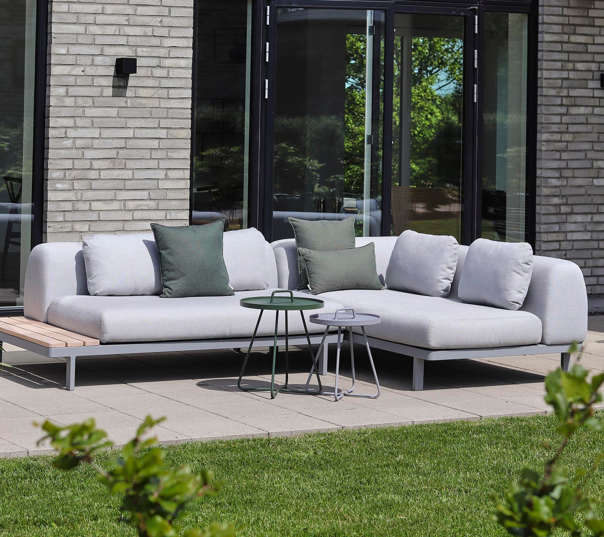 Moderne sektionelt sofa i lys stof med dekorative puder, parret med små sideborde i en rolig indstilling.
