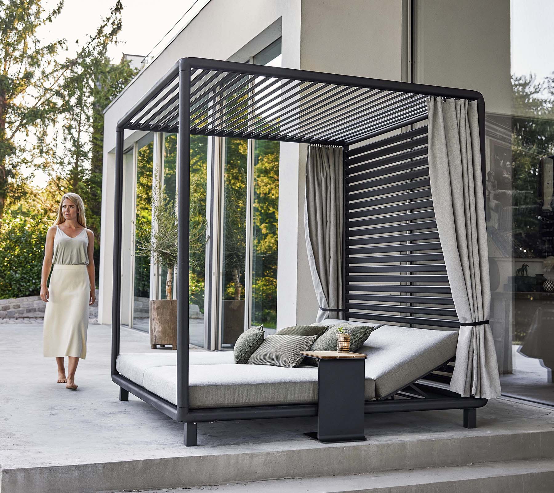 En stilfuld cabana med et moderne design, der har et komfortabelt loungeområde og bløde gardiner, beliggende i en fredelig omgivelser.
