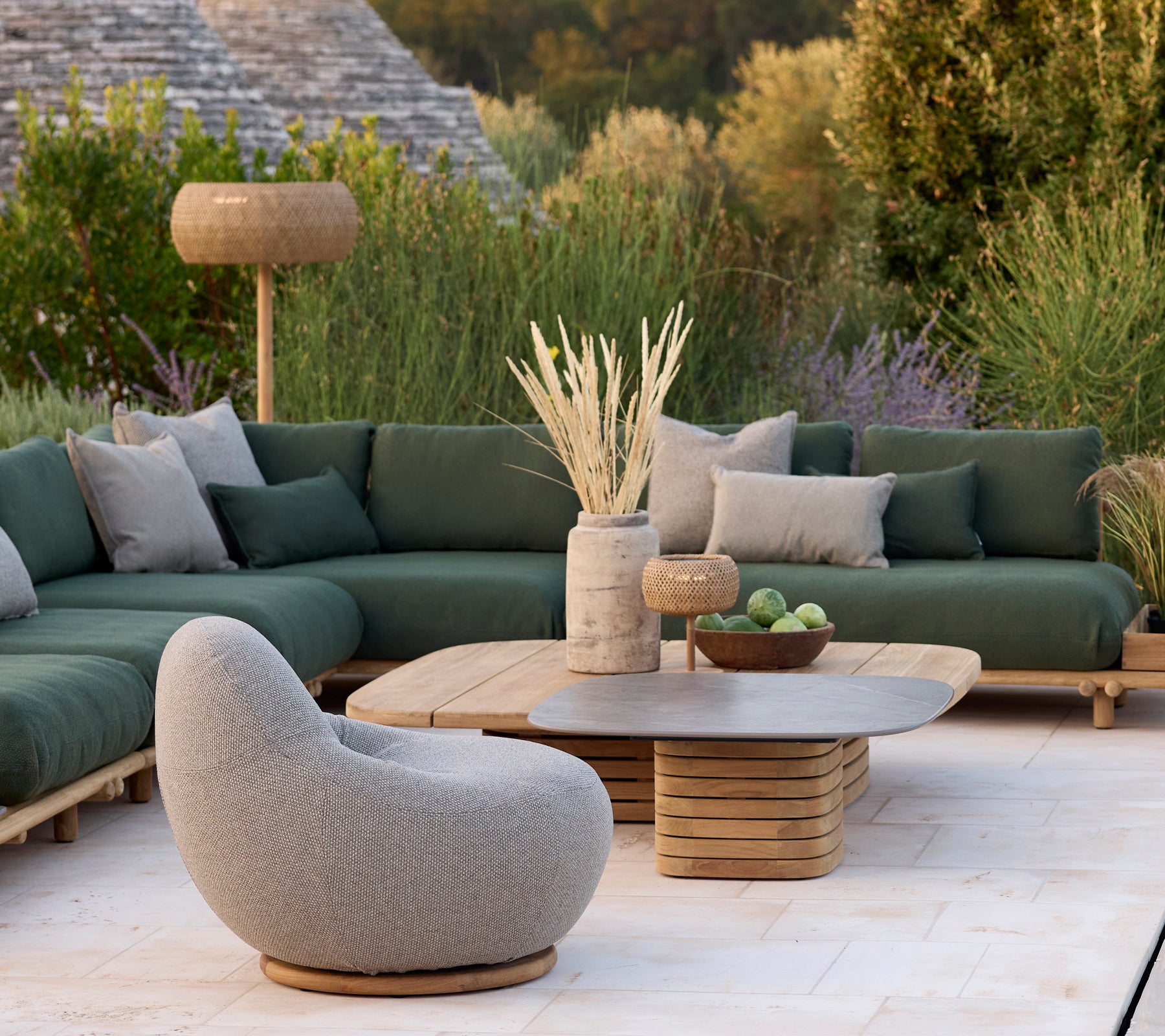 Moderne loungeområde med en grøn sofa, grå stol og rundt sofabord.