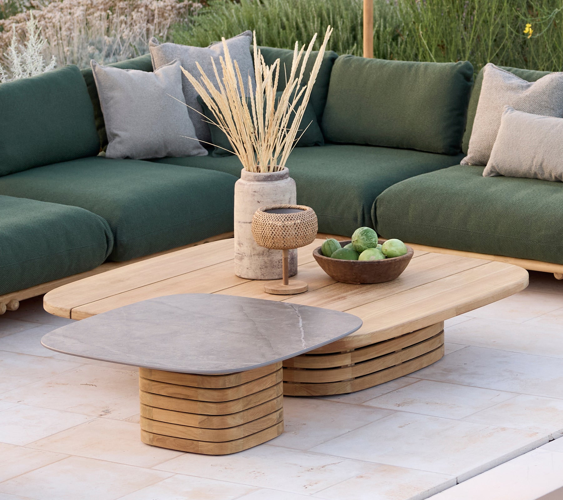 Moderne loungeområde med en grøn sofa med puder, et trækaffebord og dekorative genstande.