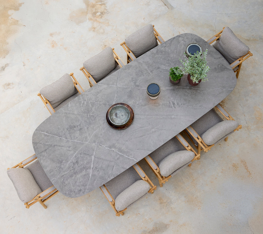 Moderne spiseopsætning med et gråt bord, beige puder og træstole.