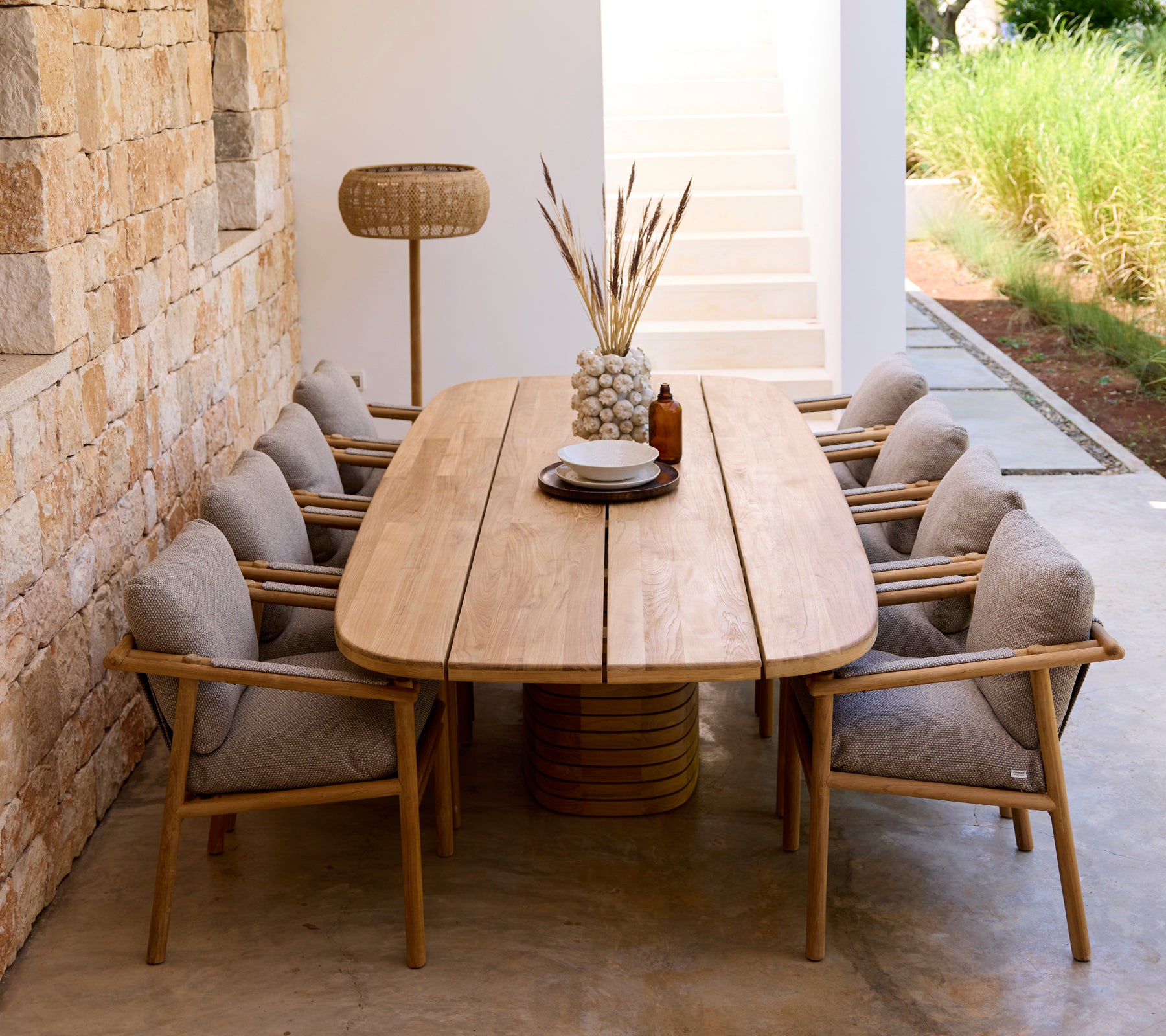 Moderne spisestue med træbord, grå puder og træstole.