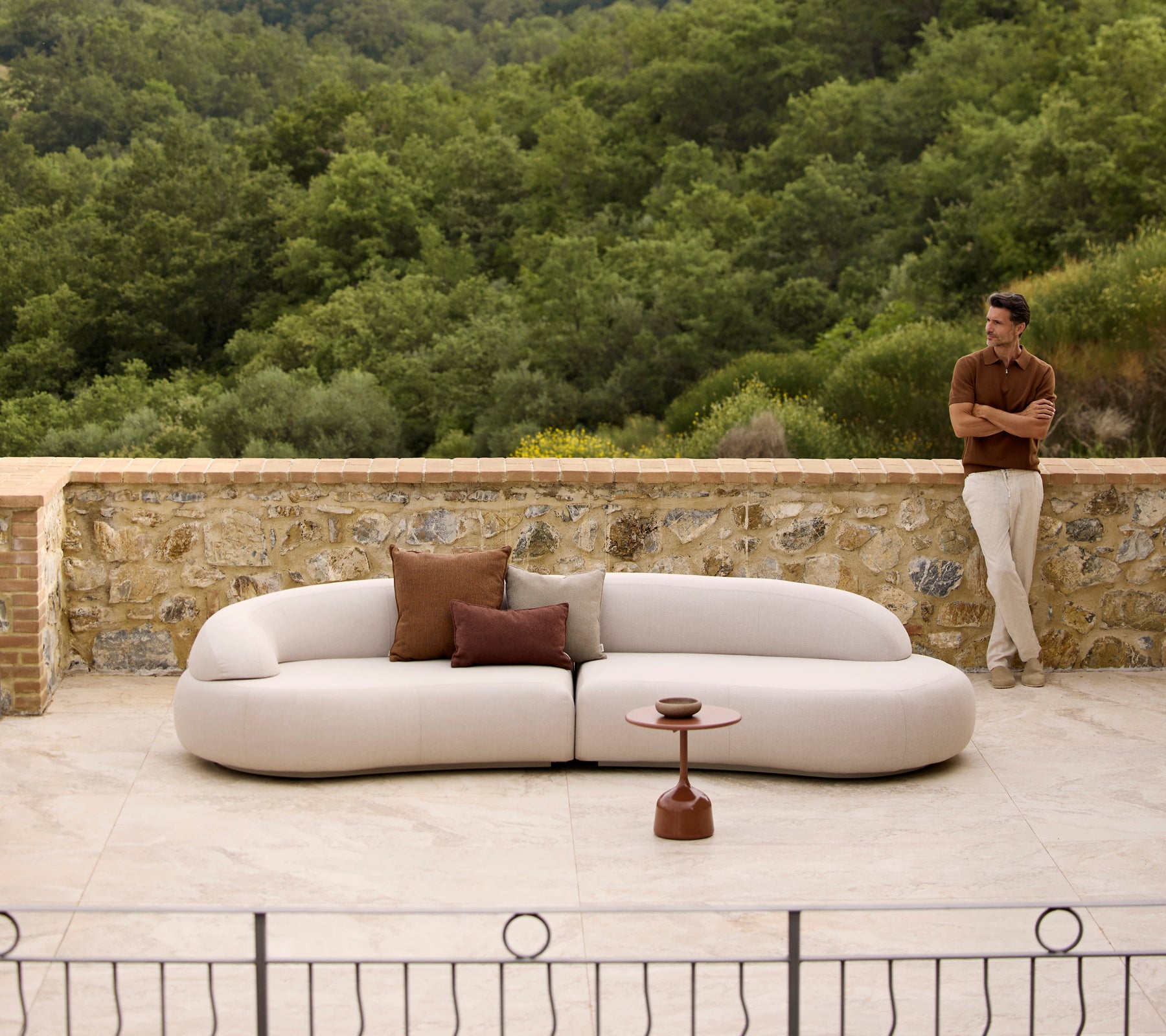 Mellow lounge sofa med Rise puder og et Glaze sofabord, placeret mod en frodig grøn baggrund.