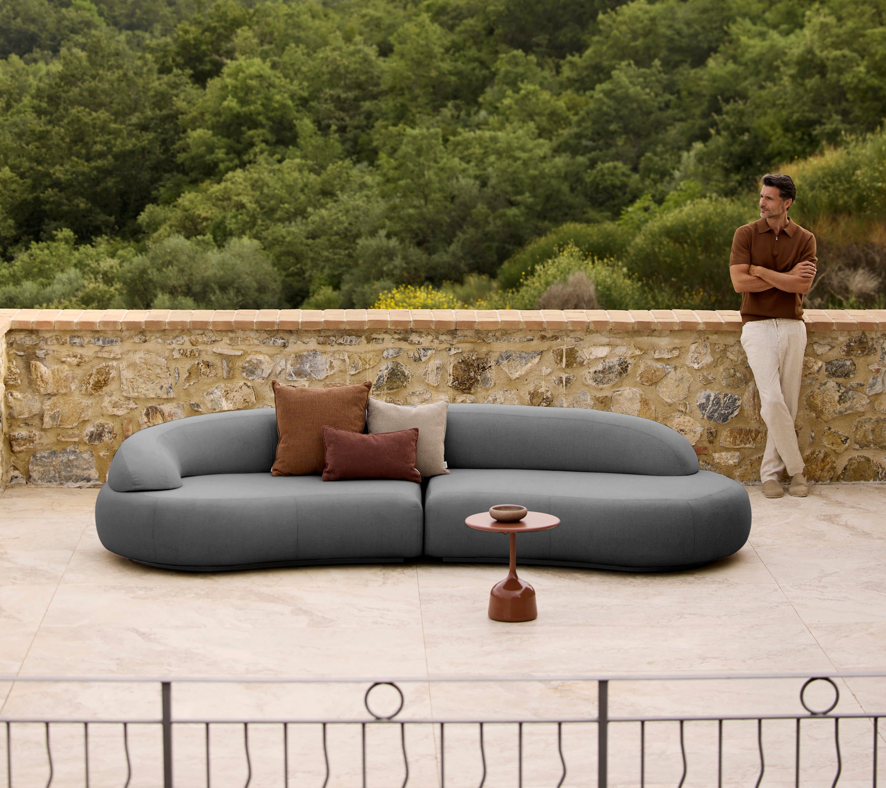 Mellow lounge sofa med puder ved siden af et elegant Glaze kaffebord, sat op imod en naturlig baggrund.