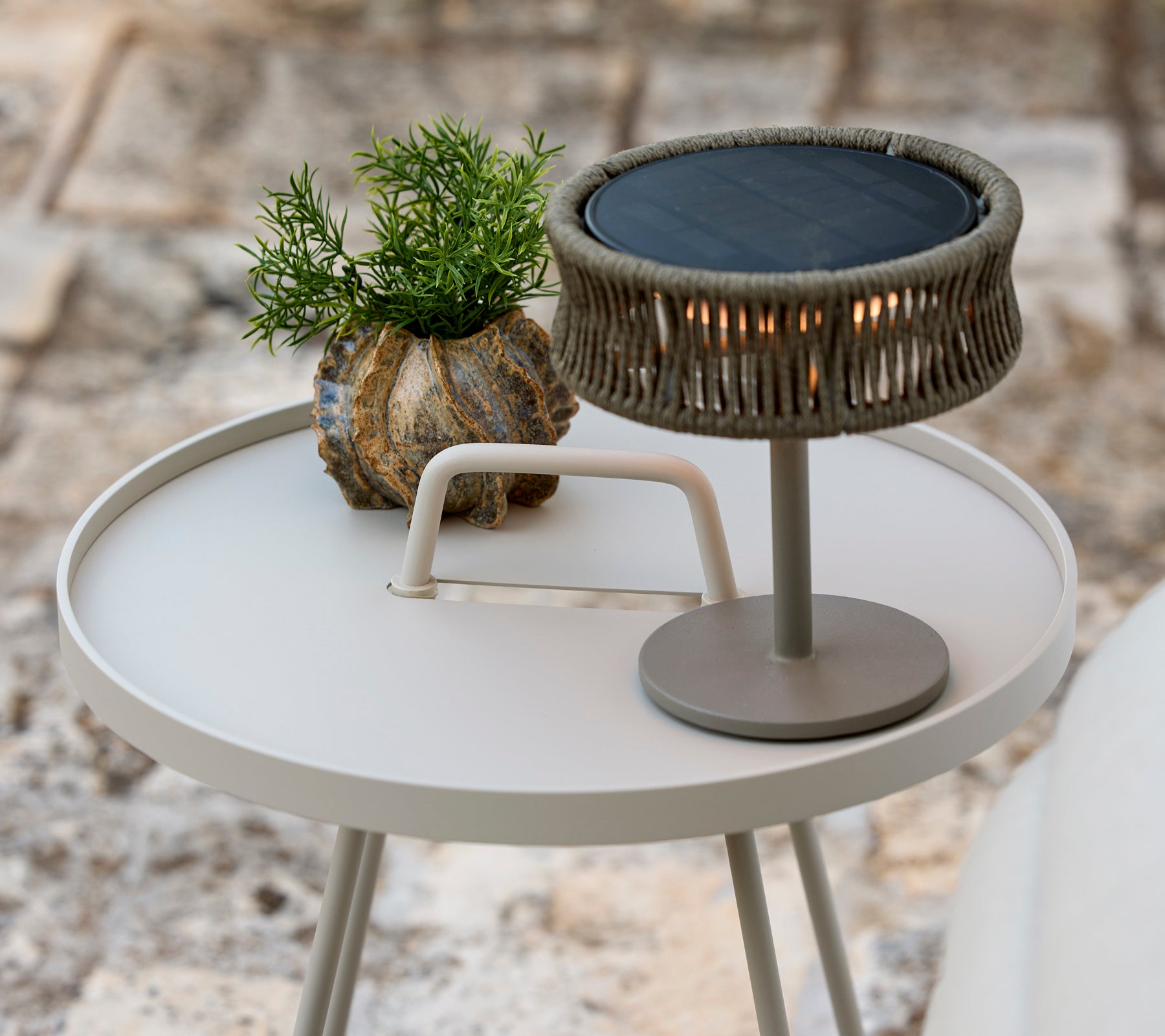 Moderne grå sidelampe med en grøn plante og en stilfuld bordlampe.